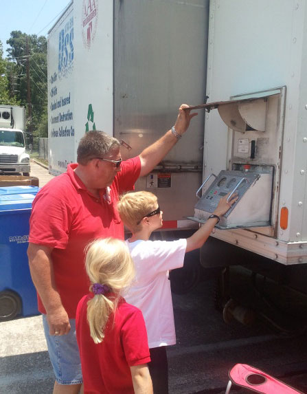 a man helping a boy with the shredding truck control panel